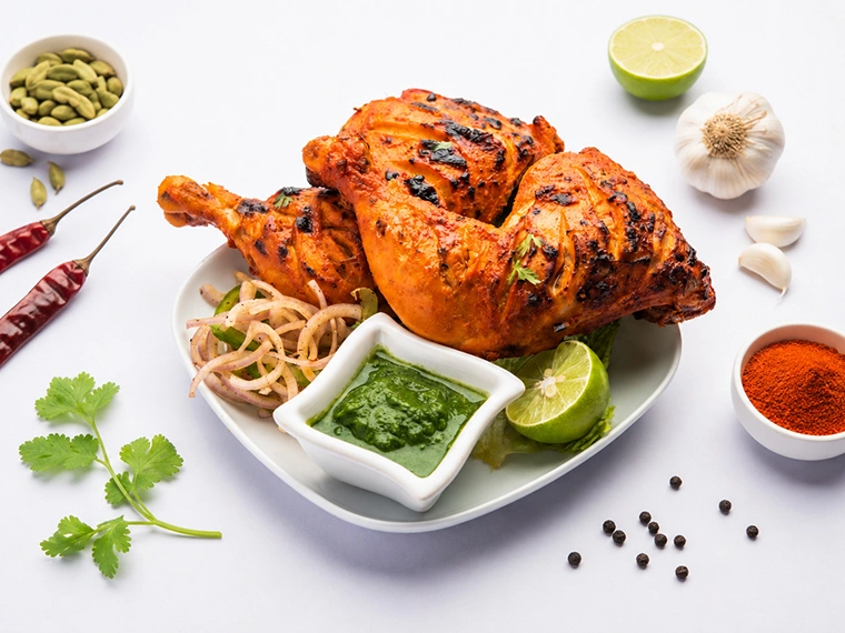 Spicy Indian tandoori chicken with salad, onion rings, lime wedge, and green mint chutney served at Best Indian restaurant in Singapore.